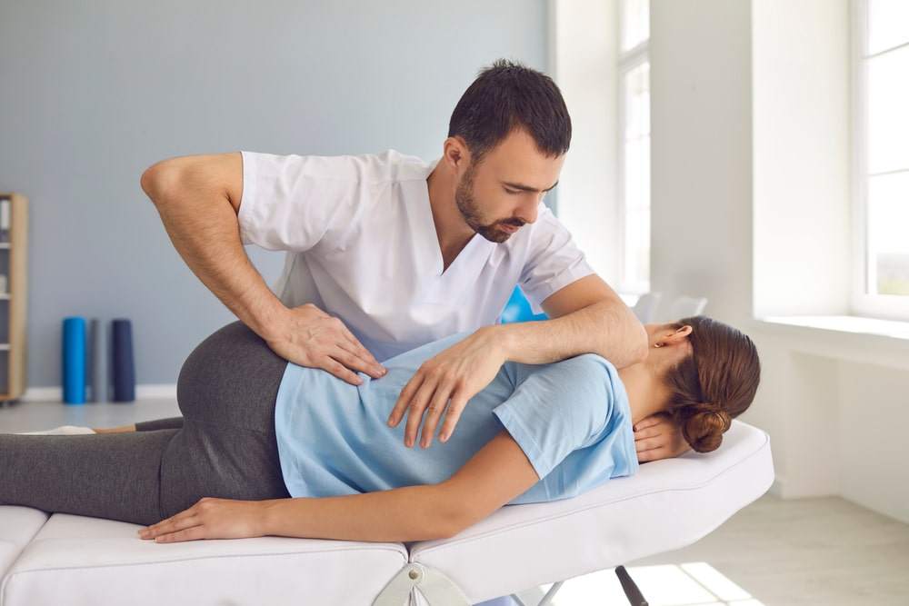 Osteopath treating young woman for back pain